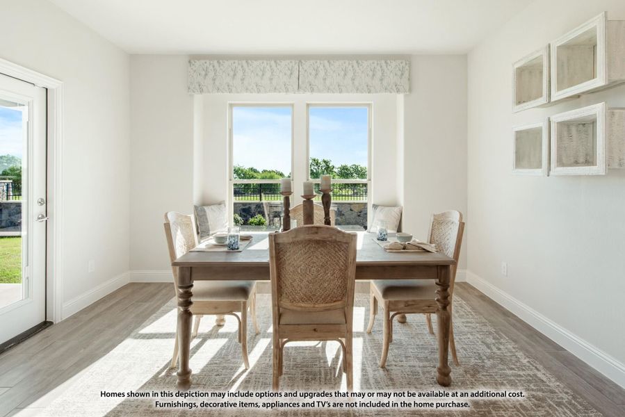 Bright dining room with wood table, six chairs, hardwood floors, and two windows overlooking a backyard patio.