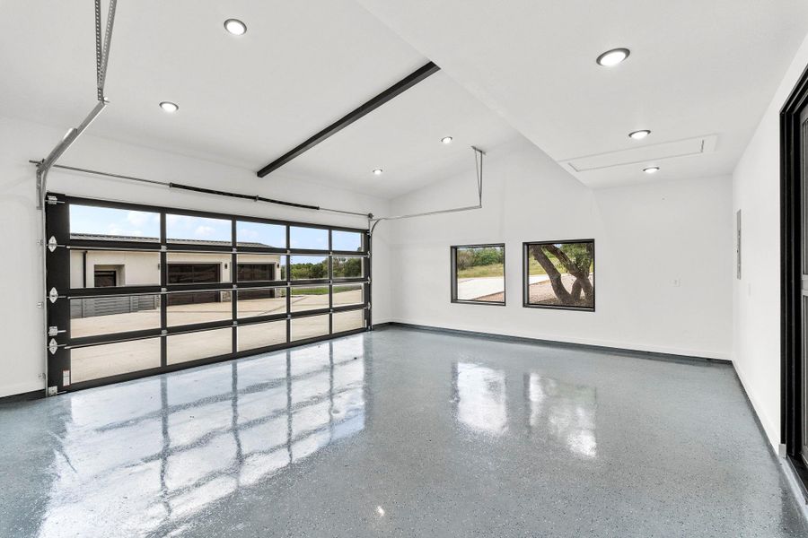 Spare room featuring healthy amount of natural light, vaulted ceiling, and dark aggregate flooring