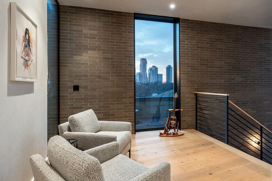 Floor-to-ceiling windows frame cityscape views from this inviting landing with sleek hardwood flooring and a contemporary staircase. Floor-to-ceiling windows frame cityscape views from this inviting landing with sleek hardwood flooring and a contemporary staircase.