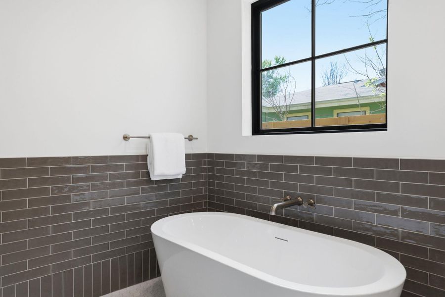 Bathroom featuring a soaking tub, tile walls, and wainscoting