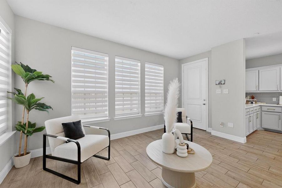 Living area featuring three windows with blinds, light-colored walls, and wood-look flooring