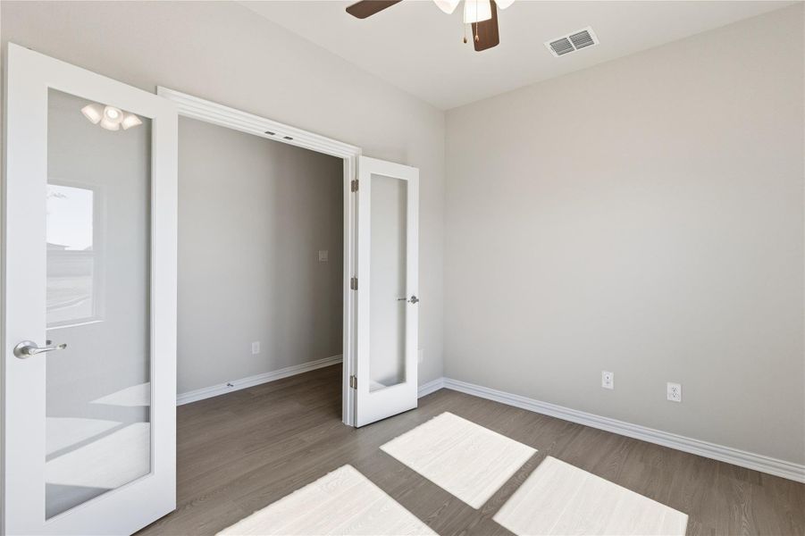 Unfurnished bedroom featuring french doors, wood finished floors, and ceiling fan
