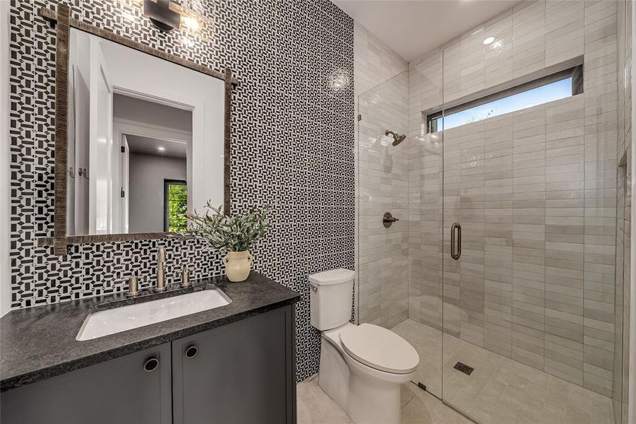 Full bath featuring tile walls, healthy amount of natural light, a shower stall, vanity, and backsplash Full bath featuring tile walls, healthy amount of natural light, a shower stall, vanity, and backsplash