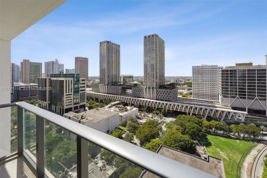 Private balcony with a metal and glass railing, featuring an expansive urban cityscape
