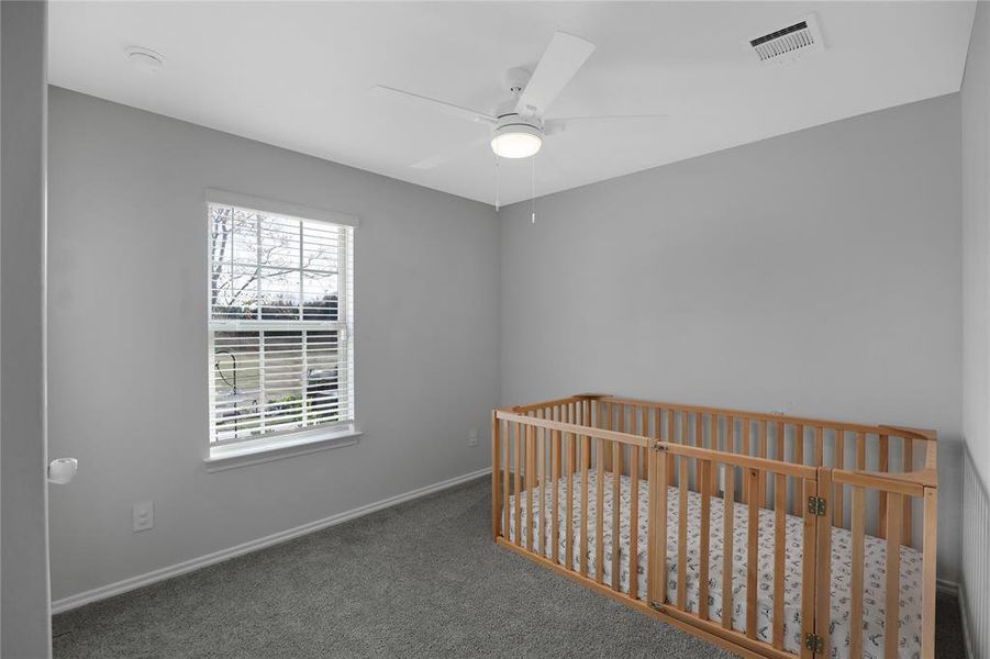 Unfurnished bedroom featuring carpet flooring, a nursery area, and ceiling fan