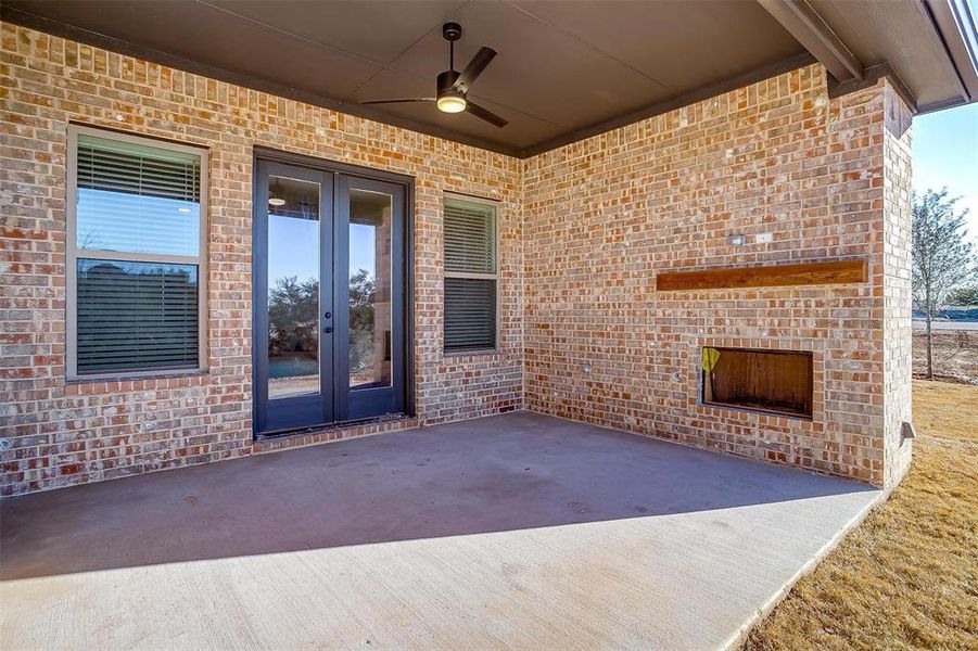 Covered back patio featuring ceiling fan and fireplace, prewired for TV