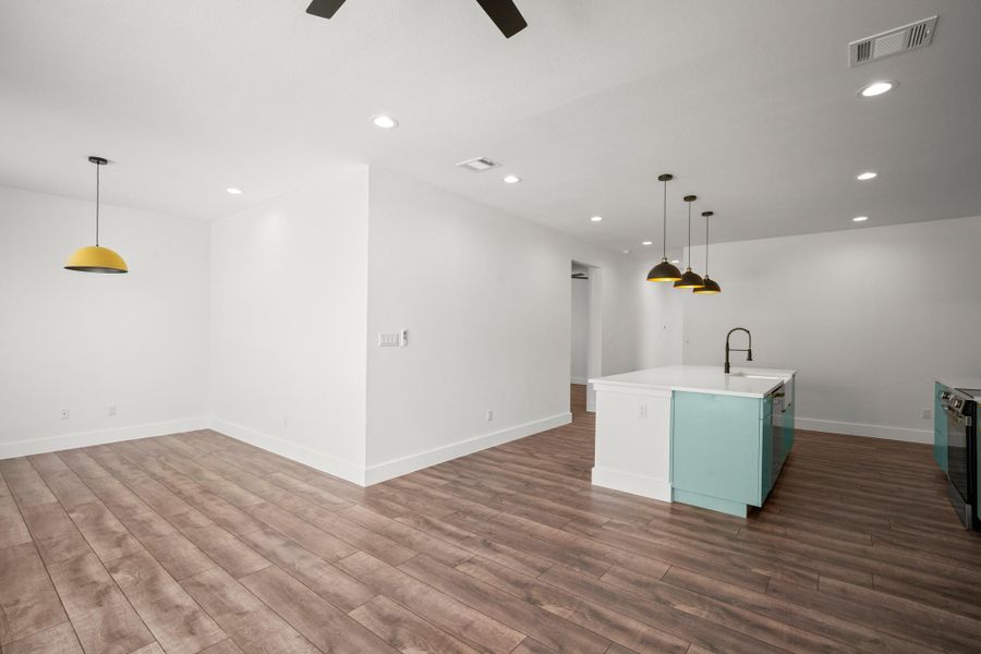 Kitchen featuring pendant lighting, an island with sink, recessed lighting, open floor plan, and dark wood finished floors