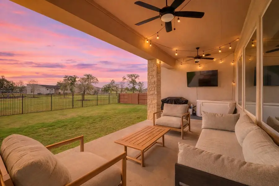 The property features a spacious covered patio with ceiling fans and string lights, providing an inviting outdoor living area