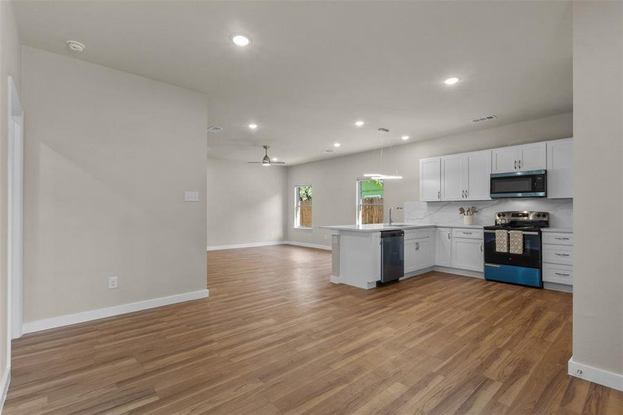 Kitchen featuring white cabinetry, open floor plan, a peninsula, appliances with stainless steel finishes, and recessed lighting Kitchen featuring white cabinetry, open floor plan, a peninsula, appliances with stainless steel finishes, and recessed lighting