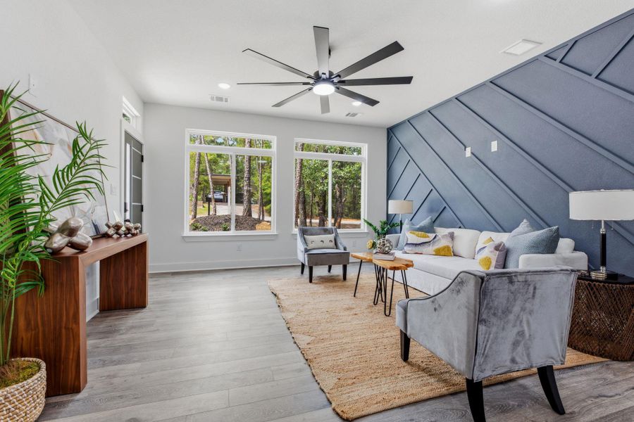 A spacious living area with tall windows overlooking a wooded setting, featuring a striking accent wall.