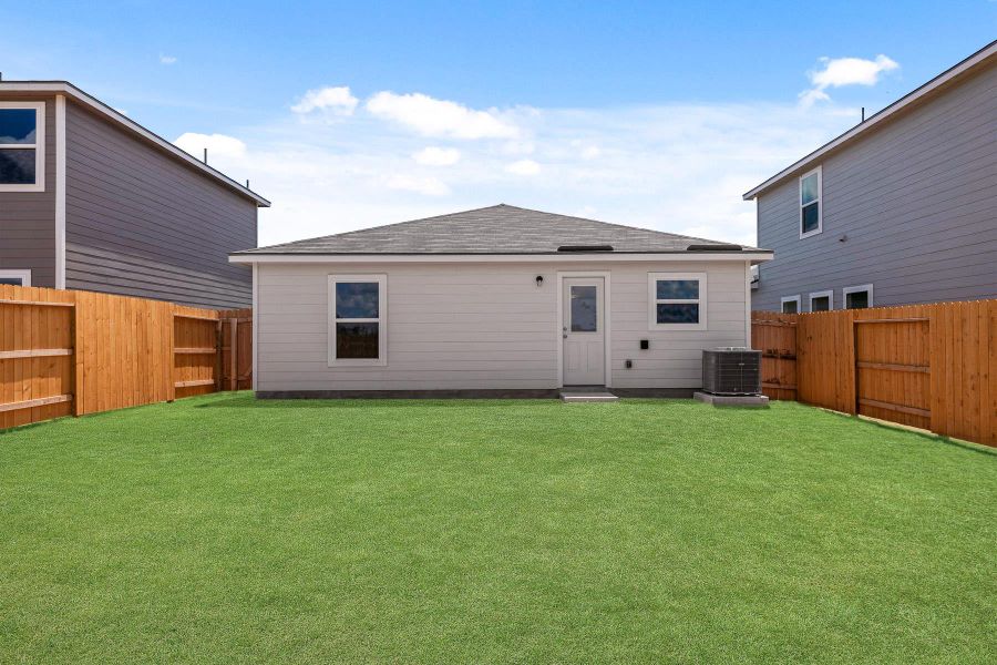 Expansive rear yard featuring a grass lawn, wood privacy fencing, and a rear exterior door Expansive rear yard featuring a grass lawn, wood privacy fencing, and a rear exterior door
