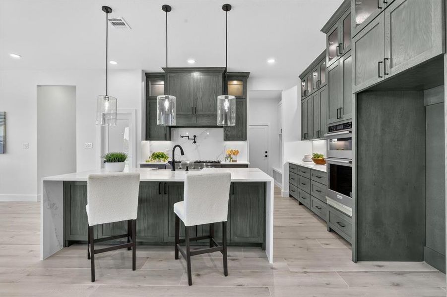 Kitchen featuring light wood-finish flooring and a central island with a waterfall countertop