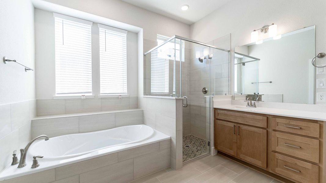 Full bathroom featuring vanity, a shower stall, a bath, and light tile patterned floors Full bathroom featuring vanity, a shower stall, a bath, and light tile patterned floors