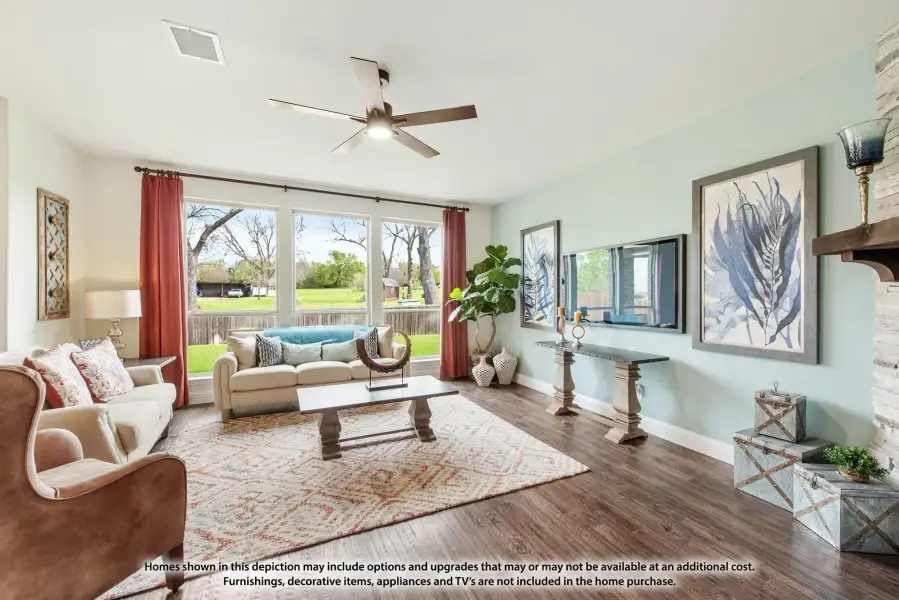 Living room with hardwood floors, ceiling fan, large windows, and stone fireplace accent wall