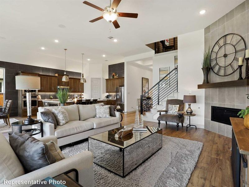 Living area featuring a tiled fireplace, recessed lighting, wood finished floors, stairway, and ceiling fan Living area featuring a tiled fireplace, recessed lighting, wood finished floors, stairway, and ceiling fan