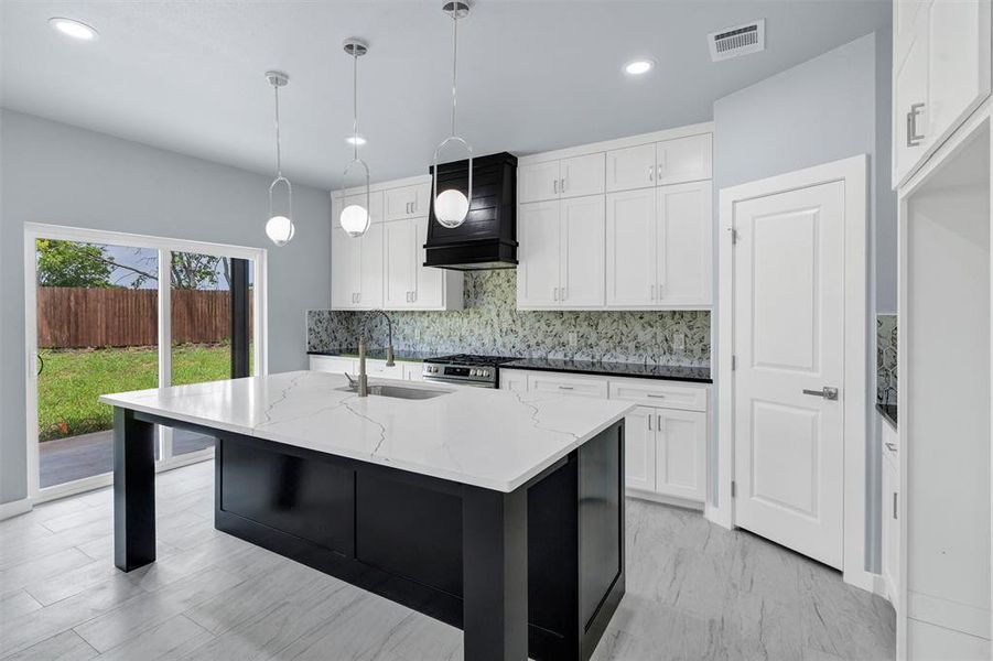 Kitchen with backsplash, premium range hood, light stone countertops, white cabinetry, and recessed lighting