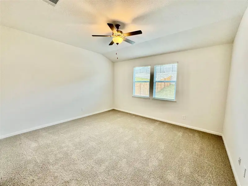 Spare room featuring carpet floors, lofted ceiling, ceiling fan, and a textured ceiling
