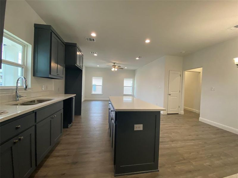 Kitchen featuring a kitchen island, a ceiling fan, dark wood finished floors, recessed lighting, and light stone counters Kitchen featuring a kitchen island, a ceiling fan, dark wood finished floors, recessed lighting, and light stone counters