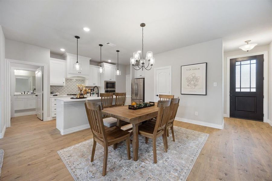 Dining area with light wood-style floors, a chandelier, and recessed lighting