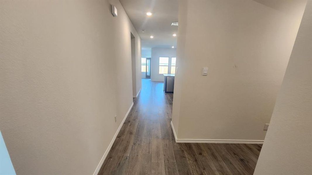 Hallway featuring wood-finish flooring, recessed lighting, and a neutral wall palette Hallway featuring wood-finish flooring, recessed lighting, and a neutral wall palette