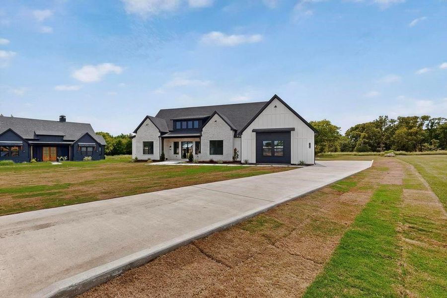 Modern farmhouse style home with a front lawn, board and batten siding, and a porch Modern farmhouse style home with a front lawn, board and batten siding, and a porch