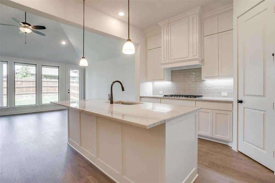 Kitchen featuring lofted ceiling, sink, hardwood / wood-style floors, and a kitchen island with sink