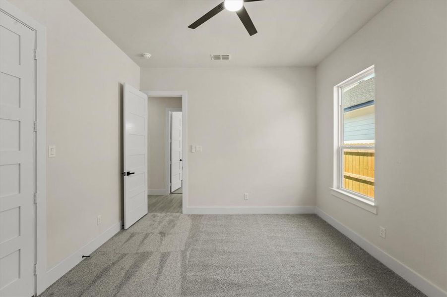 Unfurnished bedroom featuring light carpet and ceiling fan Unfurnished bedroom featuring light carpet and ceiling fan