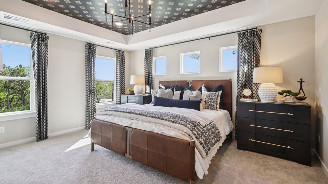 Bedroom with tray ceiling and natural light from windows
