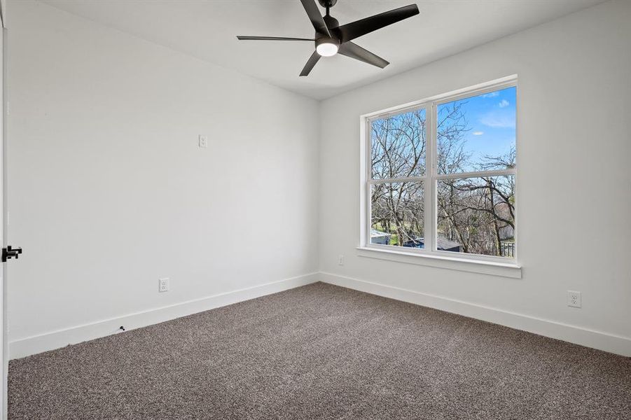 Carpeted empty room featuring ceiling fan