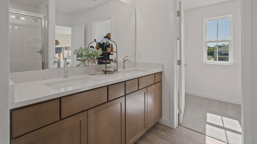 Primary suite bath with dual sink vanity and walk-in closet in a DRB Home Clementine model at the Trinity Place community.