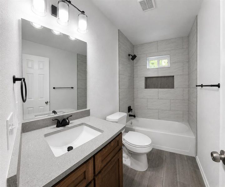 Contemporary bathroom featuring a single vanity with a light-colored countertop, wood-finish cabinetry, and a rectangular undermount sink