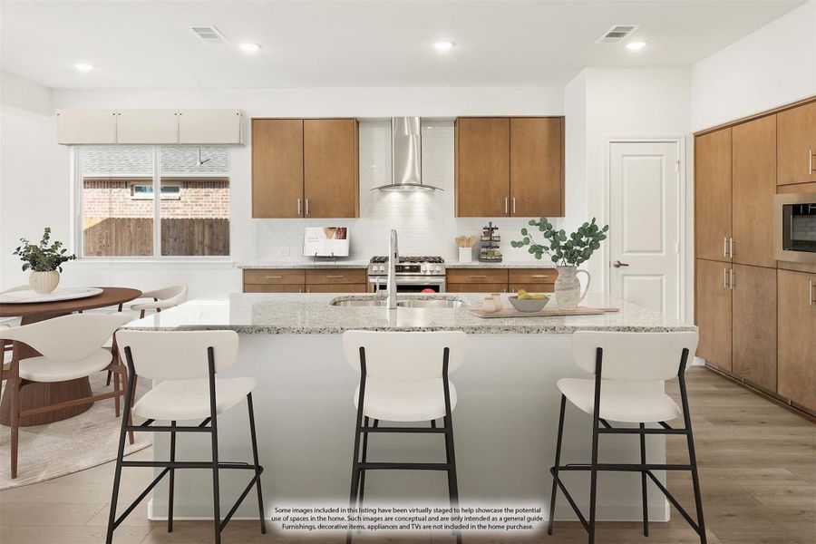 Kitchen with large granite island, three bar stools, wood cabinets, and stainless steel range hood