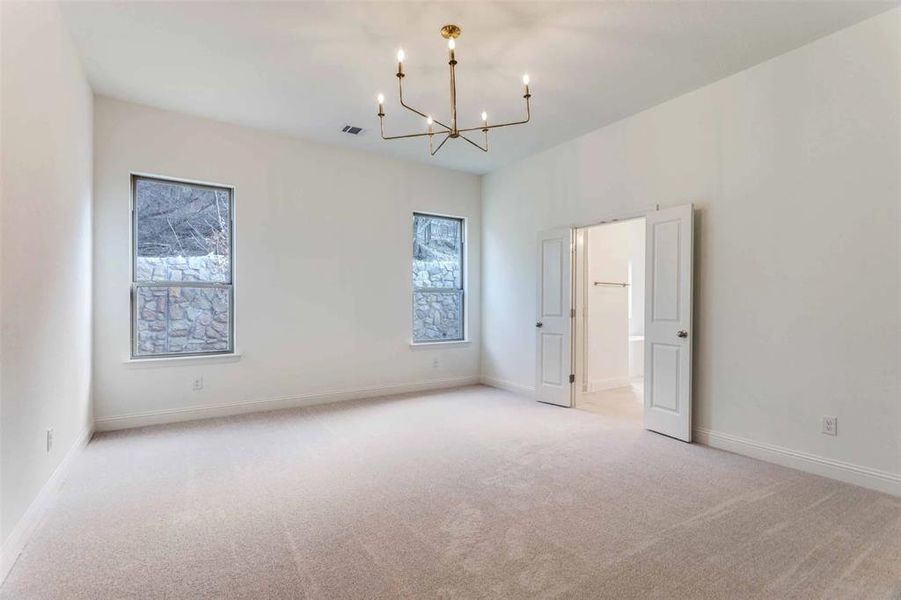 Spare room featuring light carpet and a chandelier