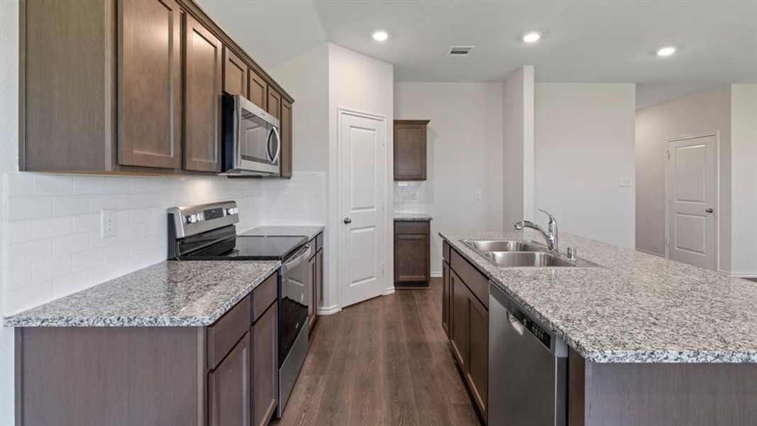 Kitchen featuring granite countertops, wood-finish flooring, stainless steel appliances, white subway tile backsplash, and recessed lighting