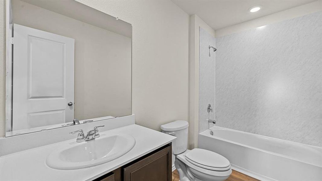 Bathroom featuring a dark wood-finish vanity, white countertop with integrated sink, chrome faucet, and a large mirror