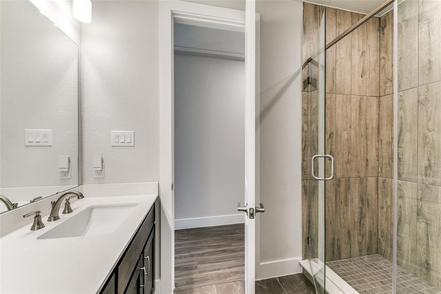 Bathroom with hardwood / wood-style floors, vanity, and a shower with shower door