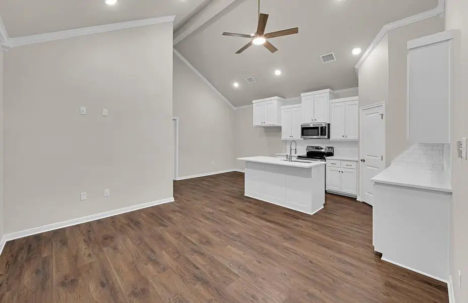 Kitchen with appliances with stainless steel finishes, crown molding, backsplash, a ceiling fan, and a center island with sink