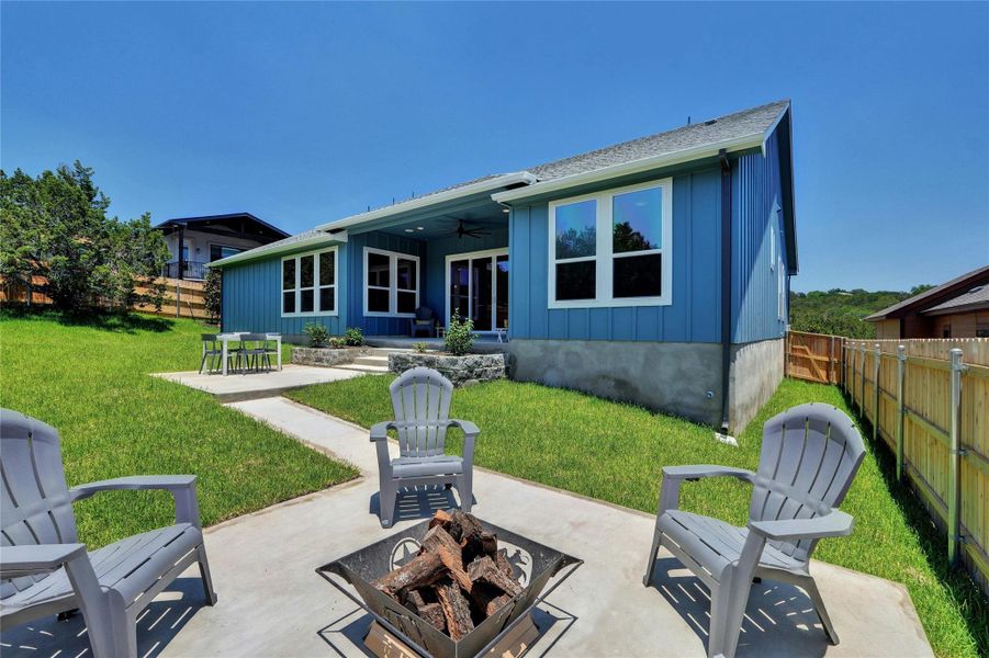 Expansive green lawn with a concrete patio featuring a fire pit