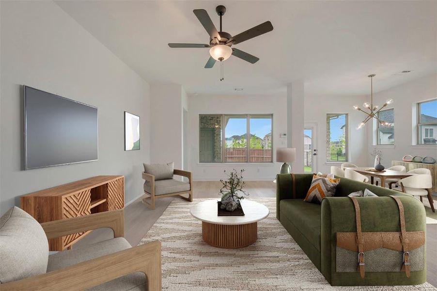 Open-concept living area featuring a ceiling fan, light wood-finish flooring, and ample natural light from multiple windows
