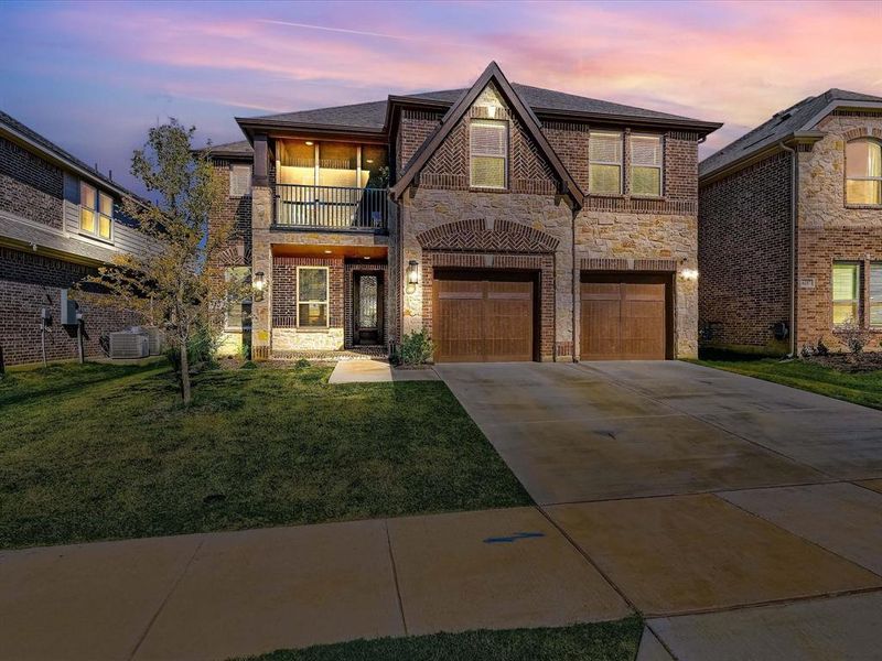 View of front of home with central AC, a yard, a garage, and a balcony View of front of home with central AC, a yard, a garage, and a balcony