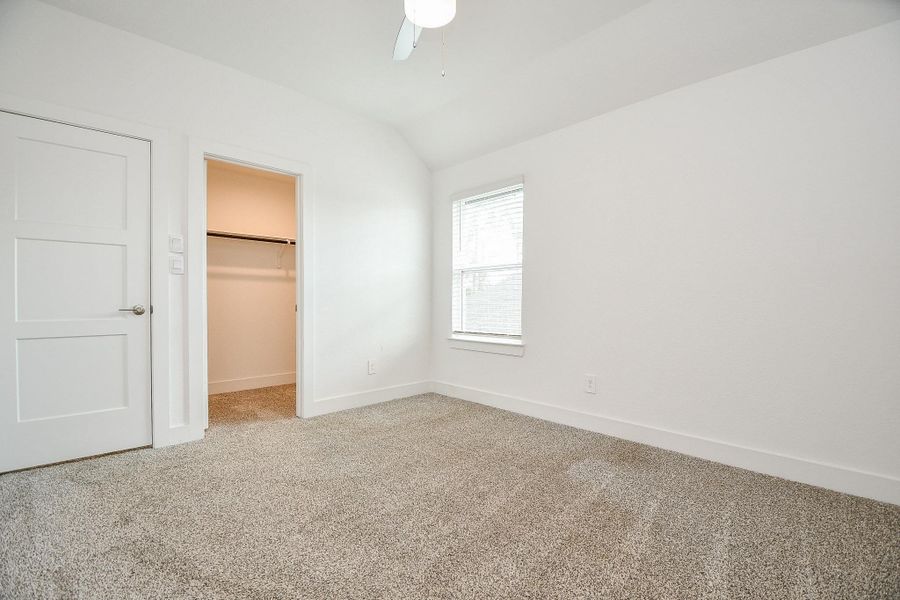 A generously sized secondary bedroom with a ceiling fan and a walk-in closet, offering ample space and comfort for residents or guests. A generously sized secondary bedroom with a ceiling fan and a walk-in closet, offering ample space and comfort for residents or guests.