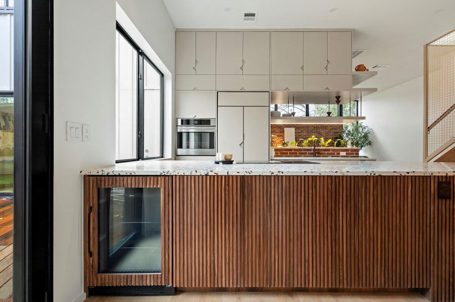Kitchen with a wealth of natural light, wine cooler, stainless steel oven, and paneled built in fridge