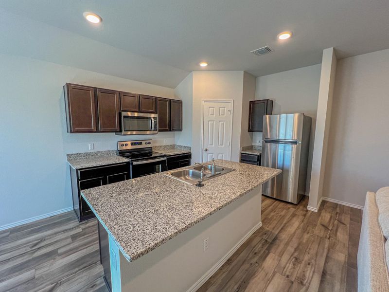 Large kitchen with stainless steel appliances open to living area