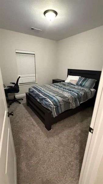 Carpeted bedroom with a desk and baseboards
