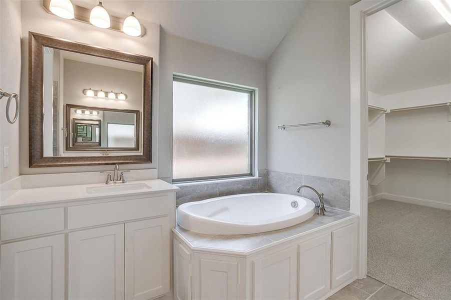 Bathroom featuring vanity, tile patterned flooring, a washtub, and lofted ceiling