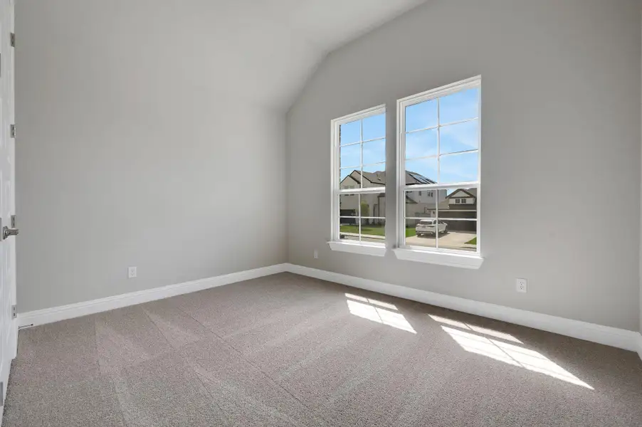 Carpeted spare room featuring vaulted ceiling and baseboards