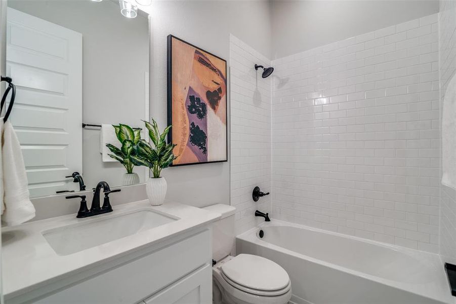 Full bathroom with vanity, tiled shower / bath combo, and toilet