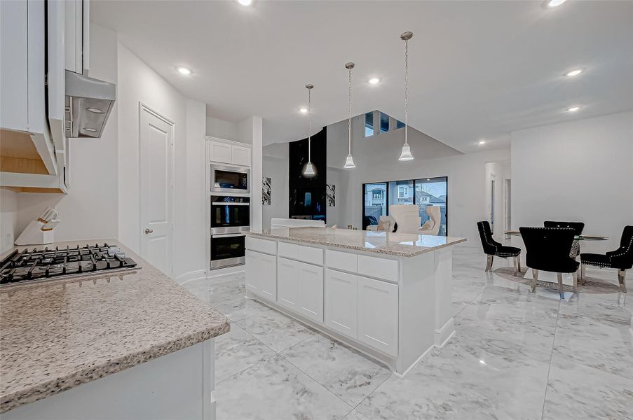 Gourmet Kitchen: A chef’s dream featuring a huge island, stainless steel appliances, double ovens, gas range, drop-down sink, and a walk-in pantry.