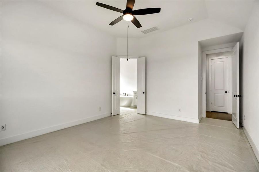 Unfurnished bedroom featuring concrete floors, a ceiling fan, ensuite bathroom, and lofted ceiling