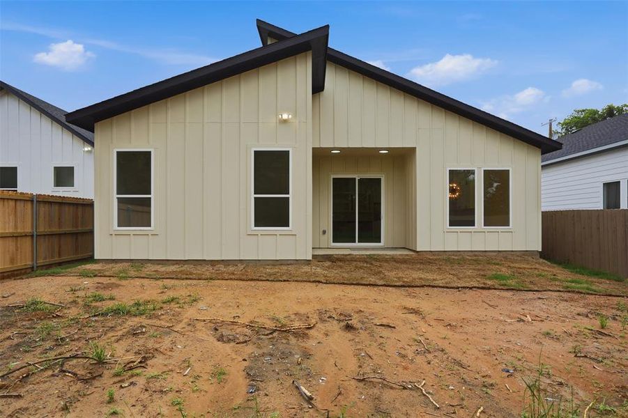 Contemporary rear exterior featuring vertical siding, a covered patio area with recessed lighting, and a sliding glass door